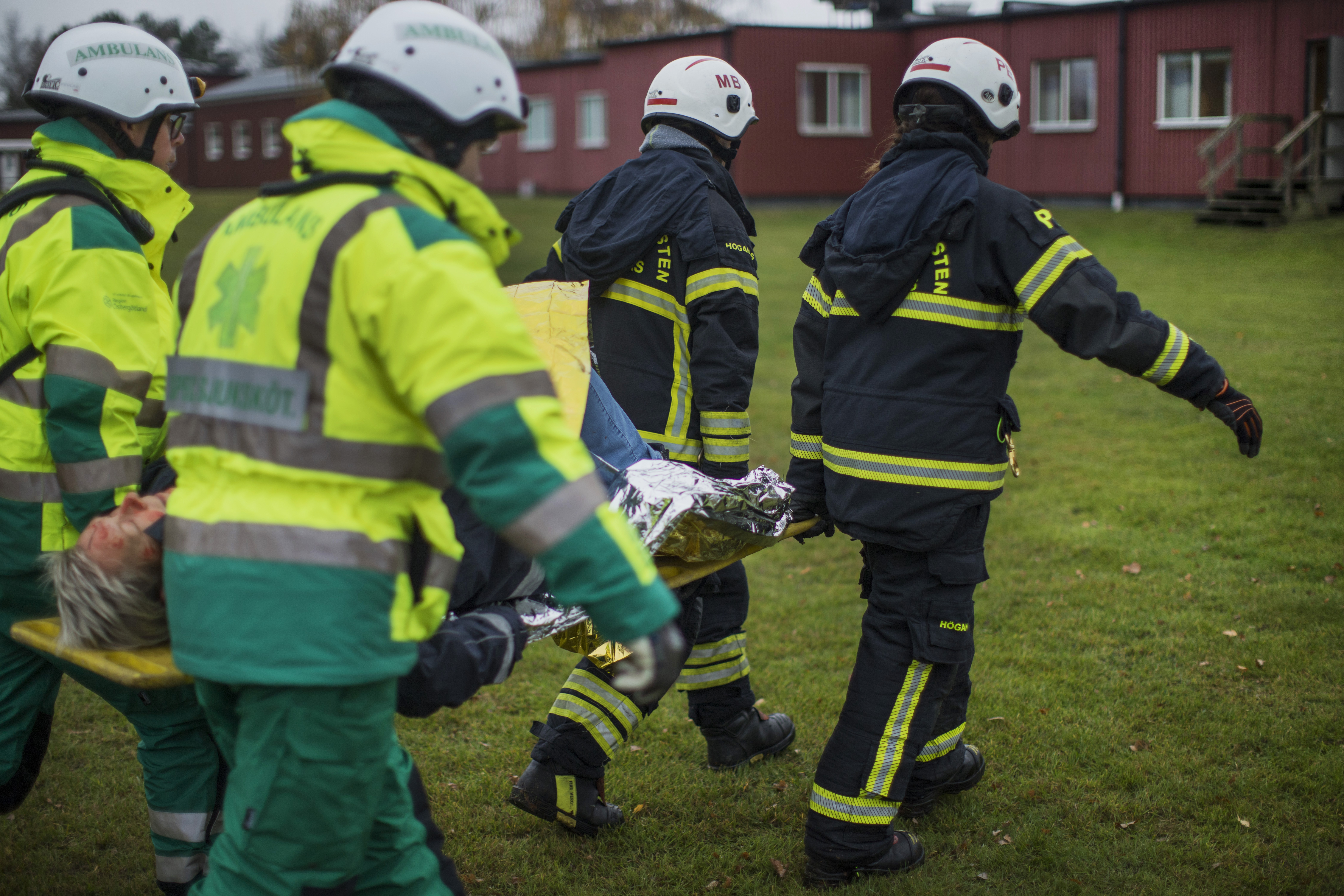 Räddningstjänstpersonal som bär en bår med en skadad person under en övning.