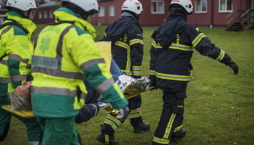 Räddningstjänstpersonal som bär en bår med en skadad person under en övning.