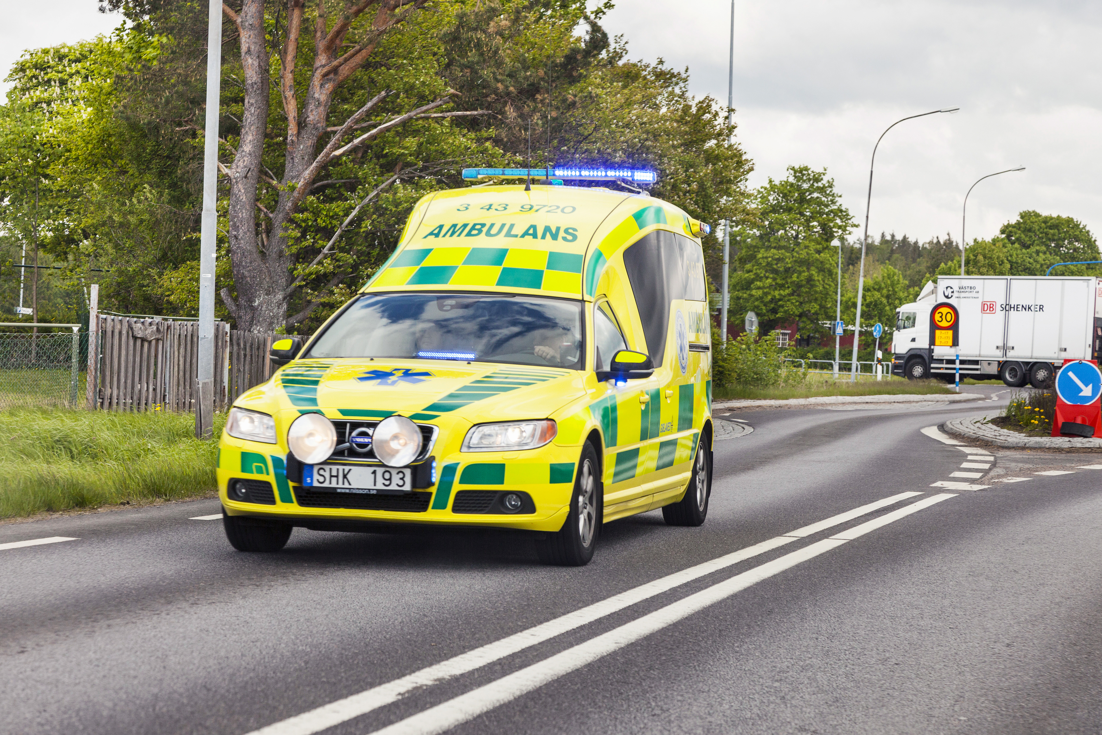 Ambulans med blåljus som kör på en väg.