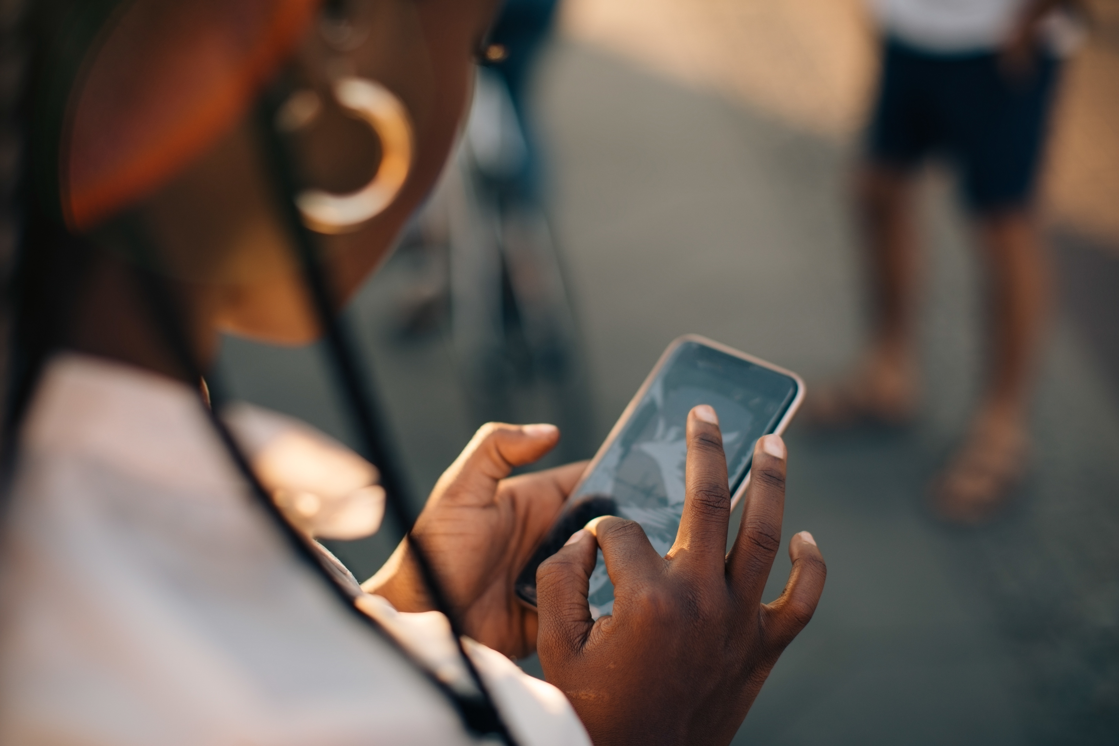 Ung kvinna som använder en mobiltelefon i gatumiljö.