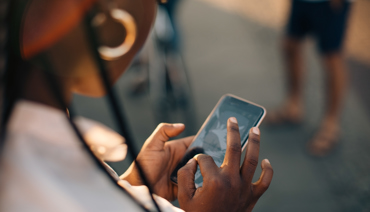 Ung kvinna som använder en mobiltelefon i gatumiljö.