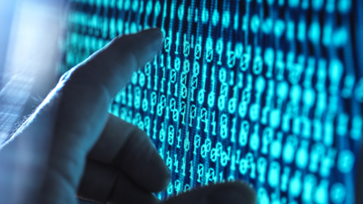 Hand som rör en datorskärm som visar binär kod