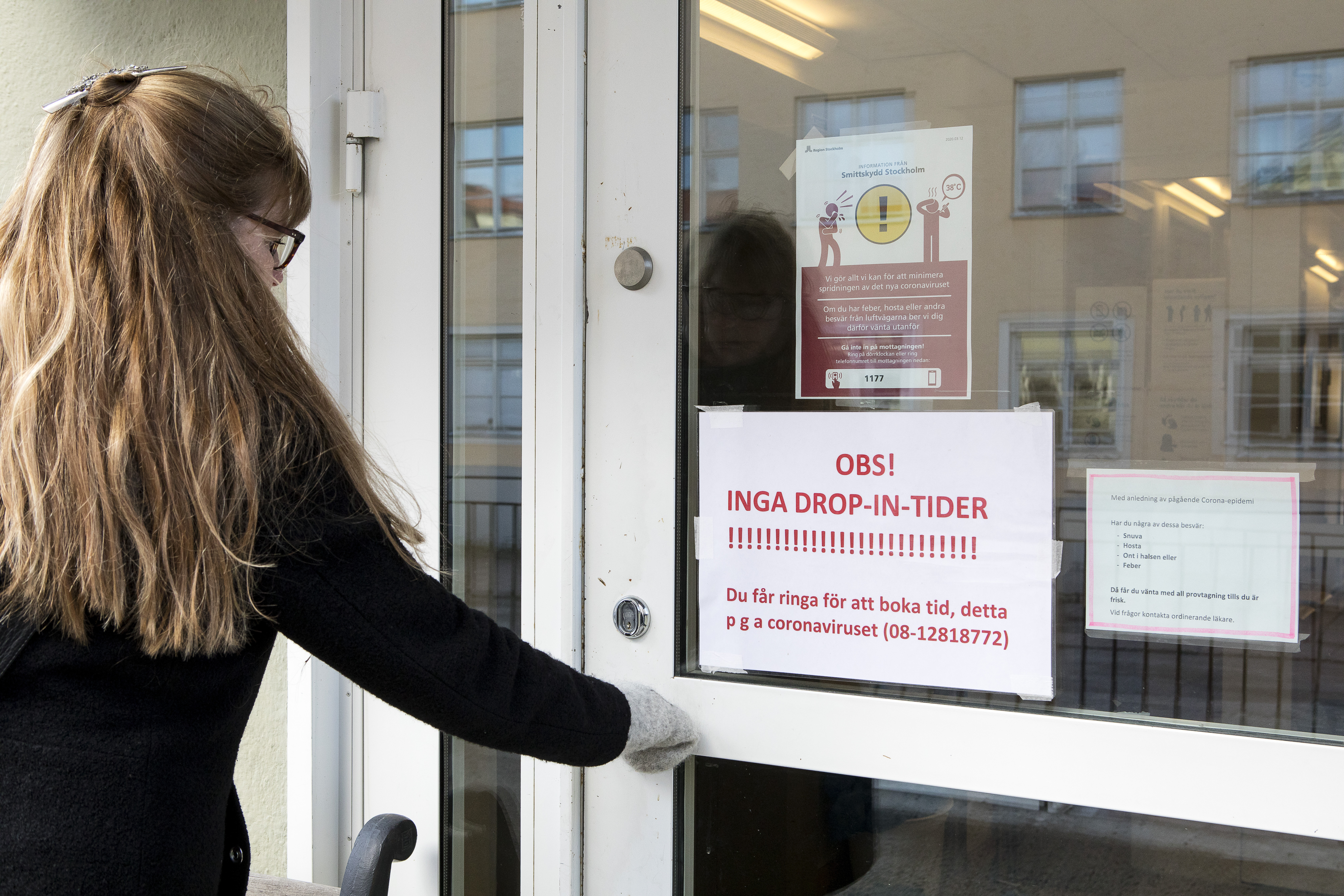 Kvinna öppnar en dörr till vårdcentral under pandemin