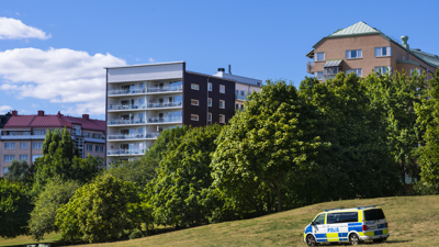 Polisbuss på en gräsmatta med höghus i bakgrunden.