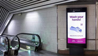 "Wash your hands" skrivet på en reklamskylt i en tom tunnelbanestation.