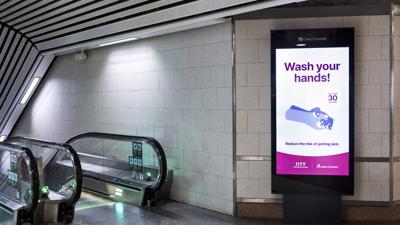 "Wash your hands" skrivet på en reklamskylt i en tom tunnelbanestation.