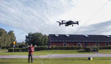Drönoperatör som flyger en drönare nära marken.