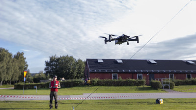 Drönoperatör som flyger en drönare nära marken.